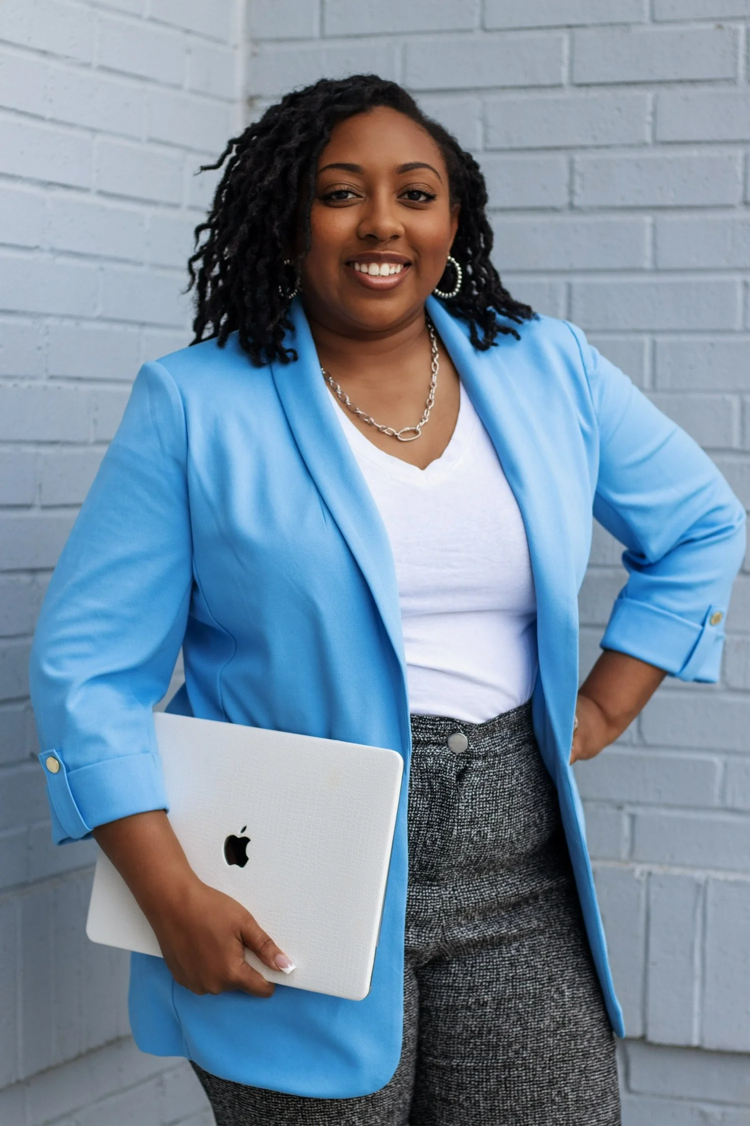 Ashley Nicole in a sky-blue blazer holding her laptop
