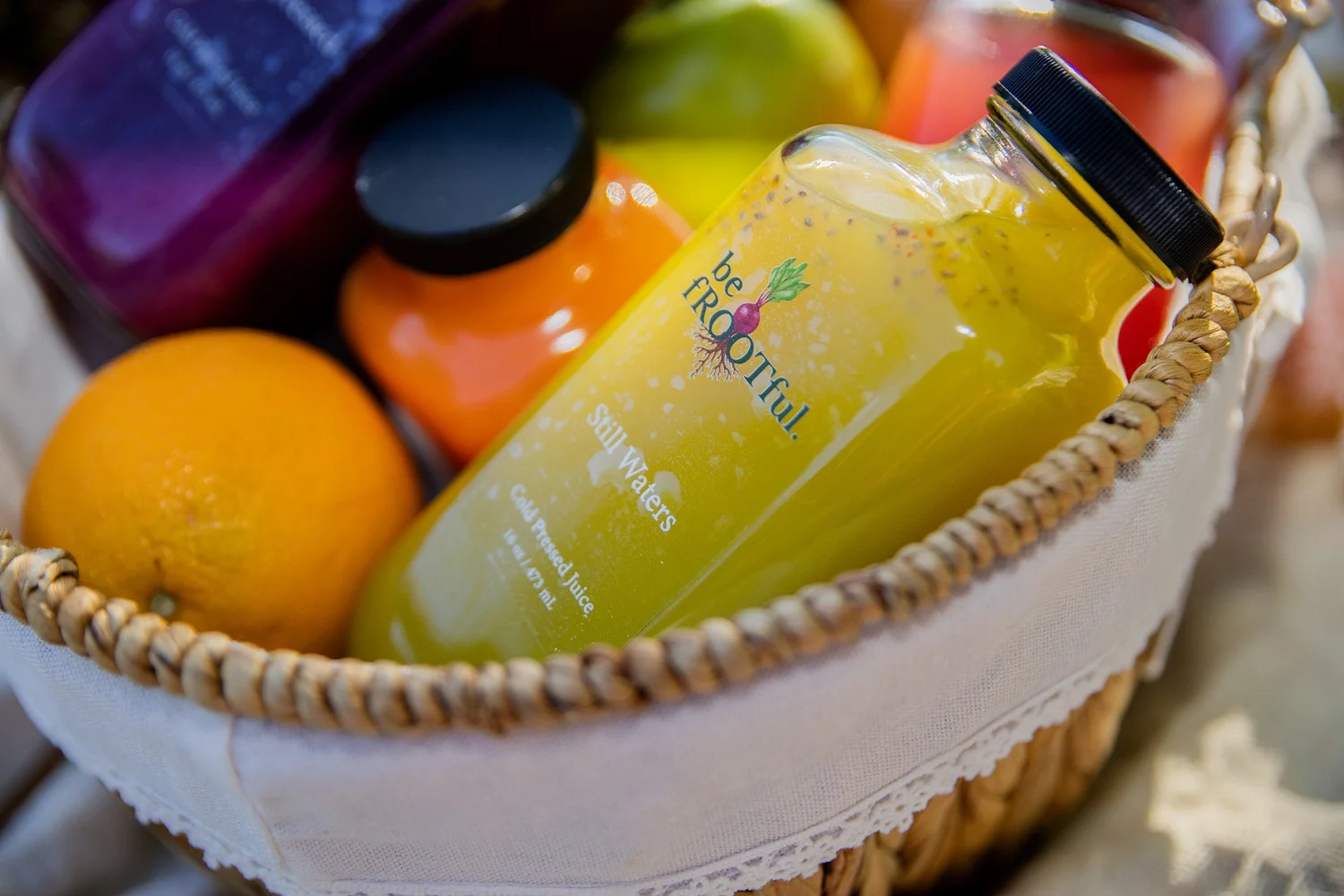 Fruit juice products photographed among citrus in a woven basket